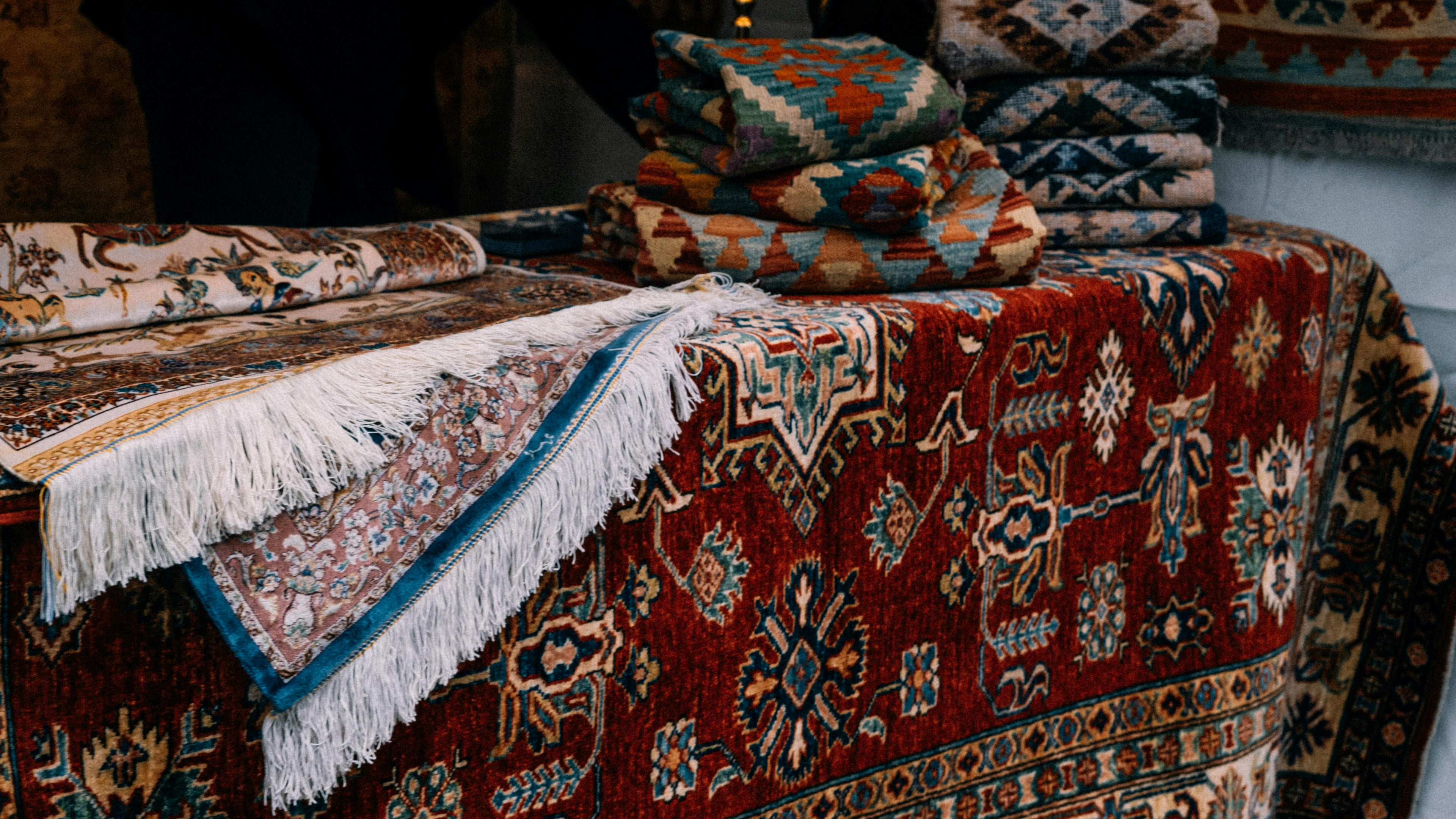 Collection of patterned rugs with intricate designs on a wooden surface.